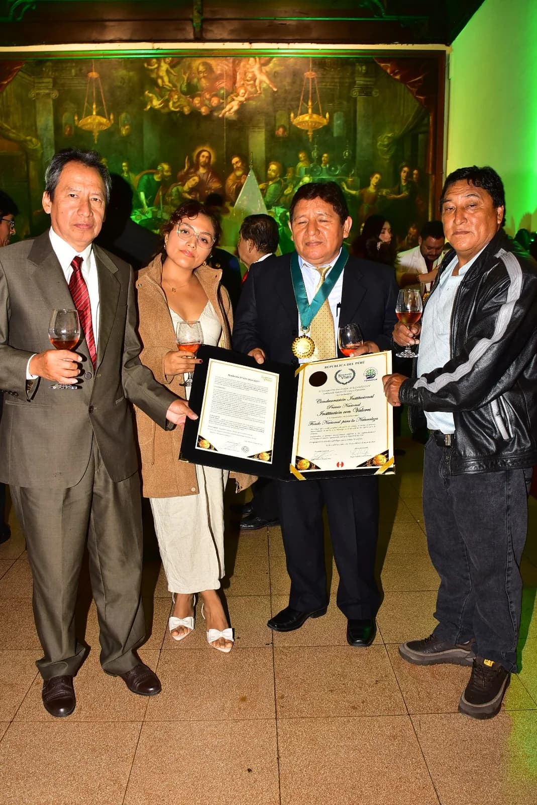 Grupo de personas mostrando una condecoración y documentos de reconocimiento.